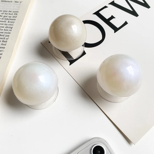Detail of pearlescent crystal ball phone grips with glitter finish on a minimal desk