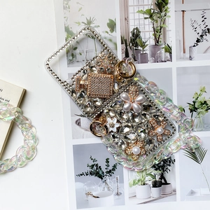 Detail of luxury rhinestone phone case with pearl accents and perfume bottle charm