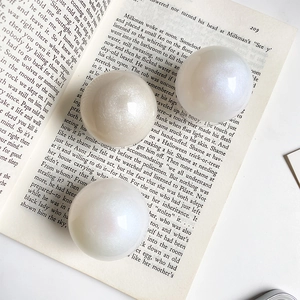 Close-up of three iridescent pearl decorative balls with fine glitter on an open book