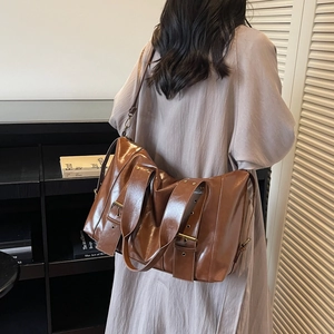 Retro brown oil wax tote bag with metal buckles shown in a minimalist lifestyle setting