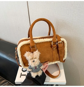 Detail of brown suede crossbody bag featuring white shearling trim and cute dog charm