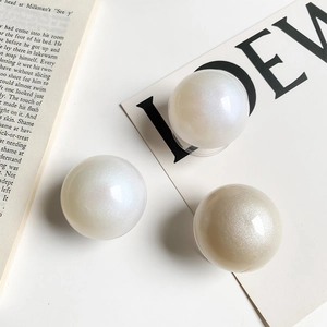 Detailed view of iridescent pearl-finish spherical phone grips on a minimalist display