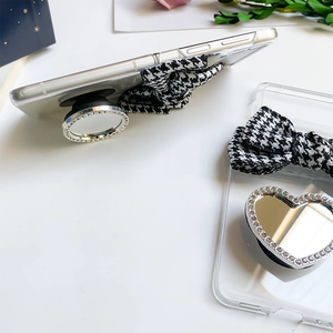 Detail of Galaxy Z Flip phone case featuring houndstooth bow and makeup mirror stand