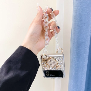 Detail of luxury rhinestone Z Flip case featuring pearl perfume bottle and iridescent chain