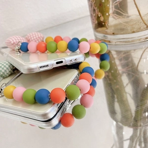 Detail of transparent Z Flip phone case with colorful beads and plaid heart pendants