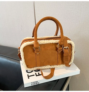Detail of brown suede handbag featuring white faux shearling trim and golden hardware