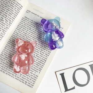 Detailed flat lay of pink and purple jelly bear phone grips with white cloud accents