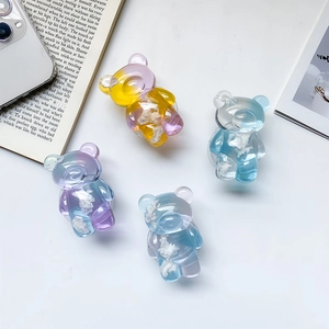 Detail of four transparent 3D bear-shaped phone grips with colorful cloud fillings on a desk