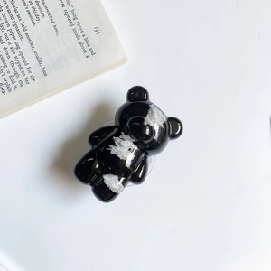 Detailed view of a trendy black bear-shaped phone grip with white marble-like texture