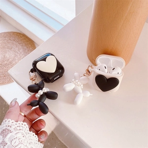 Detail of AirPods case with heart pattern and elegant balloon dog pearl keychain