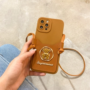 Detail of caramel brown faux leather phone case with bear emblem and crossbody strap