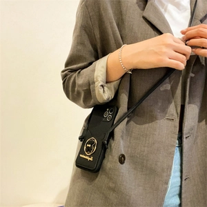 Black leather crossbody phone case with gold bear and adjustable shoulder strap worn by model