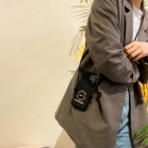 Crossbody black leather phone case with gold bear and adjustable strap worn on outfit