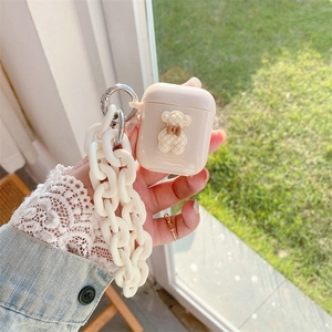 Λεπτομέρεια μπεζ θήκης AirPods με ανάγλυφο αρκουδάκι και χοντρή λευκή αλυσίδα χειρός