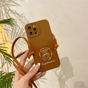 Macro detail of brown leather phone case with bear ornament and crossbody strap