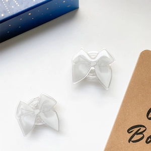 Close-up of dual white ribbon bow phone sockets with glossy acrylic trim on white desk
