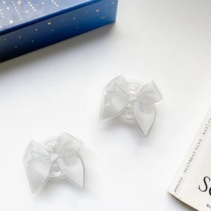 Close-up of dual light gray silk bow phone grips with transparent pop-up base