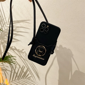 Detail of black crossbody iPhone case with gold bear emblem and card holder slot