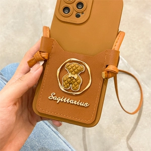 Detail of caramel phone case with card holder, quilted bear ornament and crossbody strap