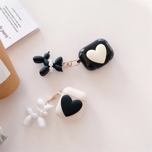 Detail view of black and cream AirPods cases with heart 3D decor and balloon dog charms