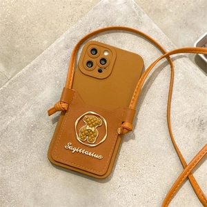 Detail of brown leather iPhone case featuring crossbody strap and bear card holder