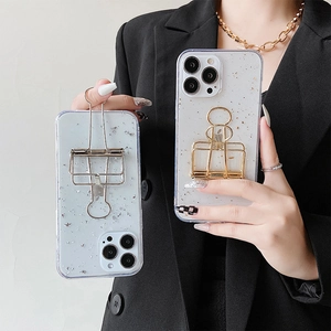 Chic iPhone case with silver foil flakes and metal long-tail clip stand shown on hand
