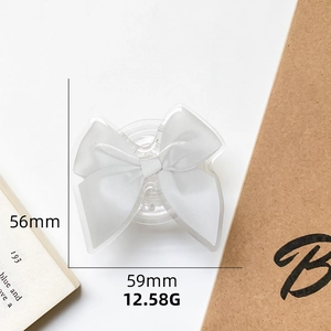 Macro shot of white satin bow phone grip with dimensions 56mm by 59mm on table