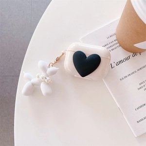 Detail of cream AirPods case featuring a 3D black heart and a cute balloon dog charm