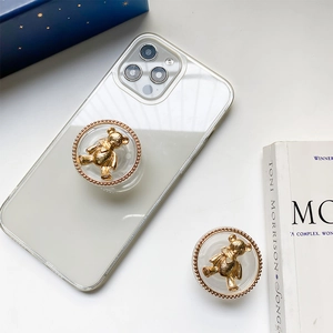 Macro detail of golden bear phone grip tok on a clear case with luxury plating