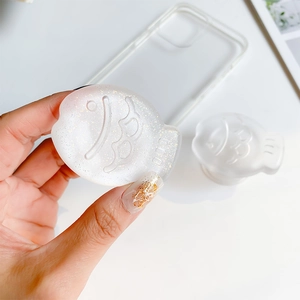 Detail of translucent cream fish phone grip with gold glitter and telescopic stand