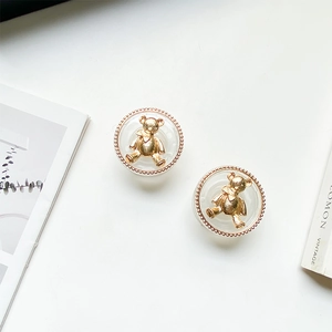 Close-up of golden bear stud earrings in vintage style with pearl-textured resin base