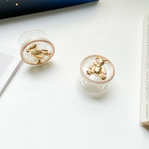 Detail of two transparent phone grips with golden bear emblems and metal bead trim