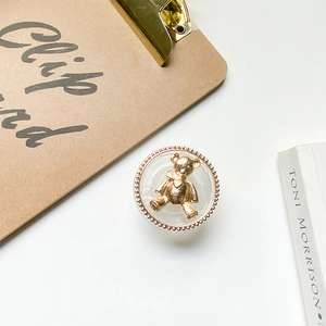 Detail of transparent phone grip featuring a gold 3D bear and rose gold beaded border