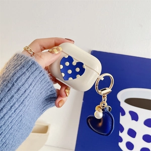 Detail of cream AirPods Pro case with blue heart and pearl charm held by model