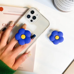 Détail d'un support de téléphone fleur bleue tenu sur un fond de bureau minimaliste