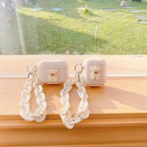 Χαριτωμένη θήκη AirPods με αρκουδάκι σε κρέμα και λευκή αλυσίδα σε φόντο με γρασίδι