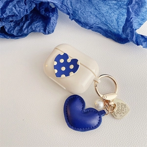 Detail of cream wireless earphone case with Klein blue heart pendant and pearl keychain