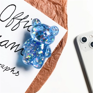 Transparent blue glitter bear phone socket stand with sparkling sequins on paper background
