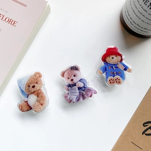 Detailed macro view of three cute acrylic bear phone griptoks on a desk surface