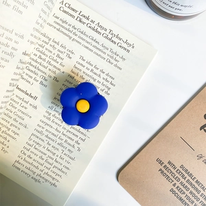 Détail du support de téléphone fleur bleue mate sur un magazine et dossier