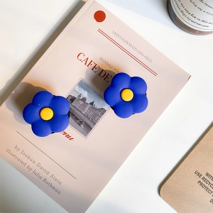 Détail de deux supports de téléphone fleur bleu Klein posés sur un livre pour le décor