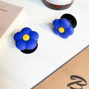 Détail du support téléphone en fleur bleue et jaune sur un bureau au style minimaliste