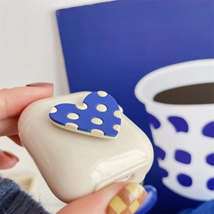 Macro shot of cream silicone AirPods case featuring a 3D blue polka dot heart detail
