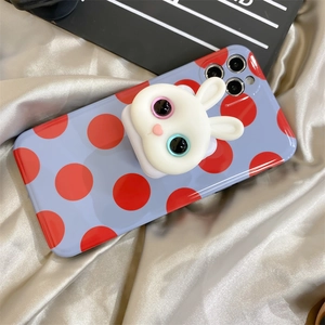 Close-up of cute 3D bunny pop socket on light blue polka dot phone case on silk cloth