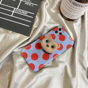 Detail of blue polka dot phone case featuring a 3D brown bear pop socket on silver silk