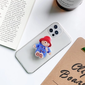 Detailed view of a 3D Paddington Bear pop socket on a clear phone case at a desk