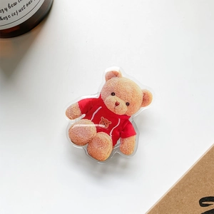 Macro view of cute teddy bear acrylic phone grip with red hoodie on a white desk