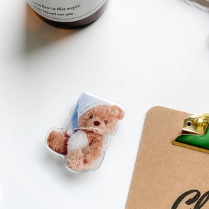 Detailed view of cute teddy bear phone grip made of acrylic on a clean white desk