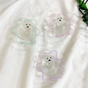 Détail de trois supports de téléphone ours transparents aux contours rose, vert et violet