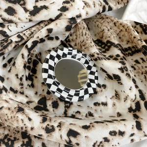 Detail of checkered pattern phone grip with built-in makeup mirror on leopard background